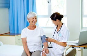 Elderly woman receiving blood pressure check from a doctor – senior healthcare services for regular health monitoring.