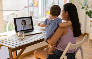 Mother consulting a doctor on call through video consultation for her baby during flu season at home